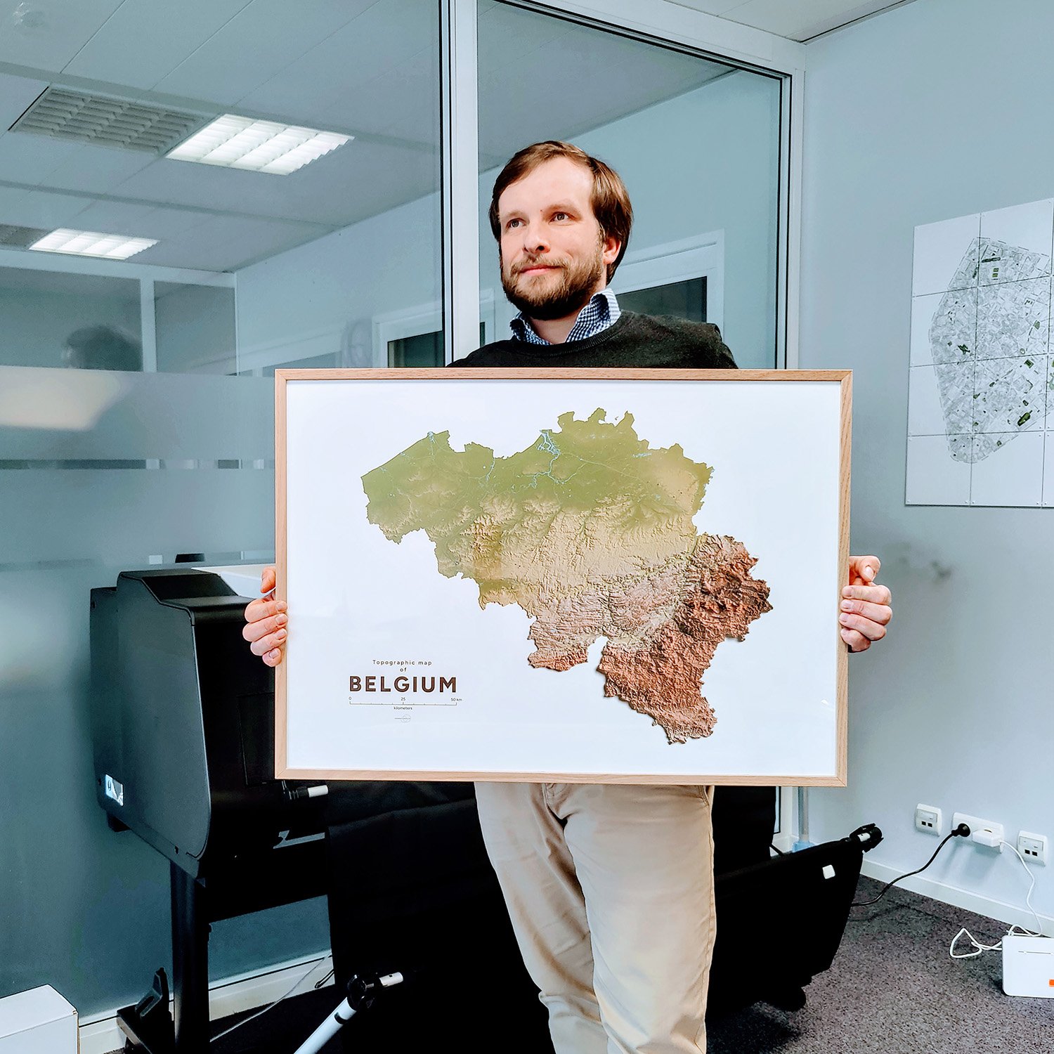 Le designer Christophe Penners avec un poster de la carte de la Belgique.